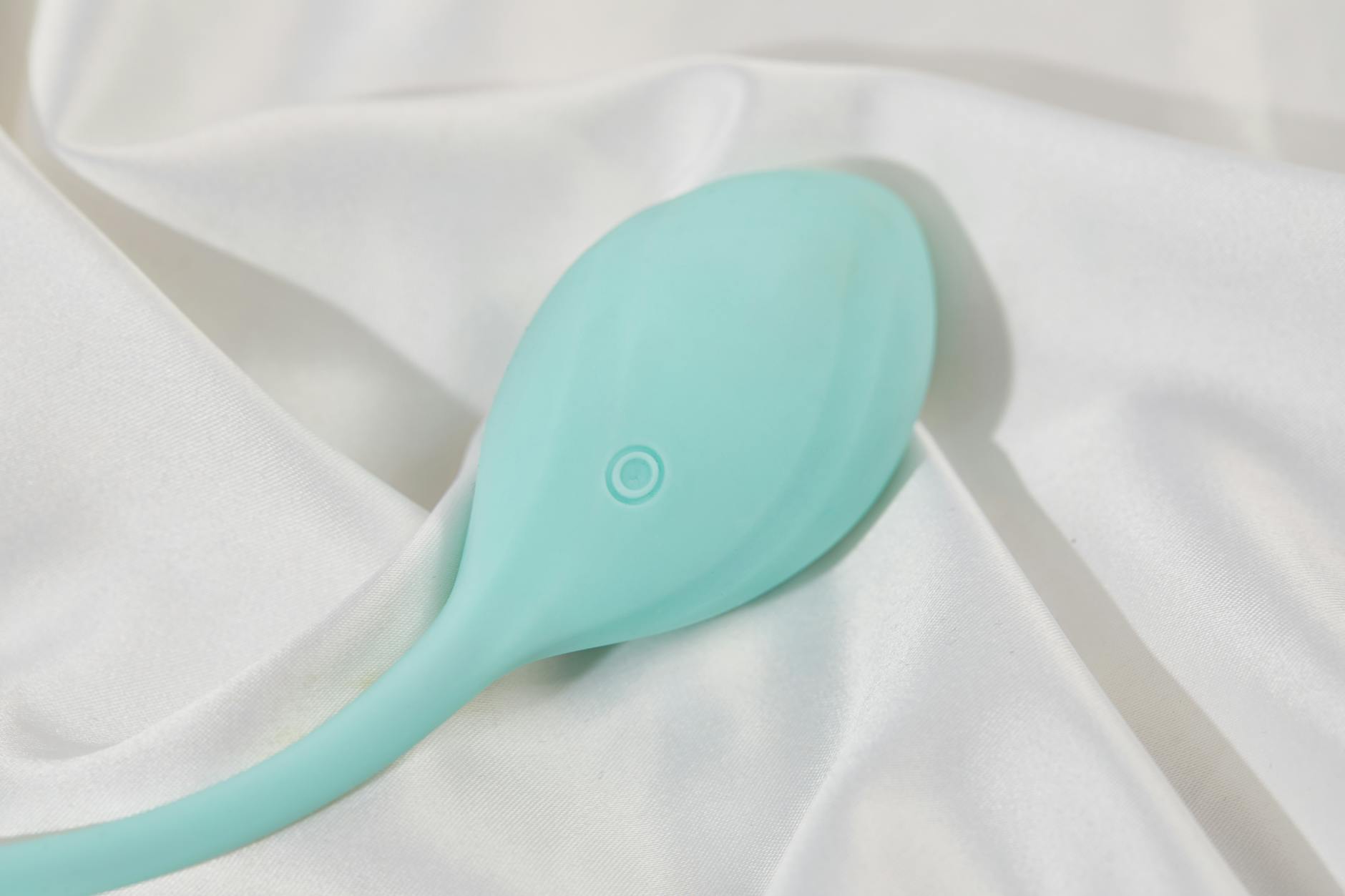 A teal lemon clitoral vibrator on soft white fabric, symbolizing gentle self-care