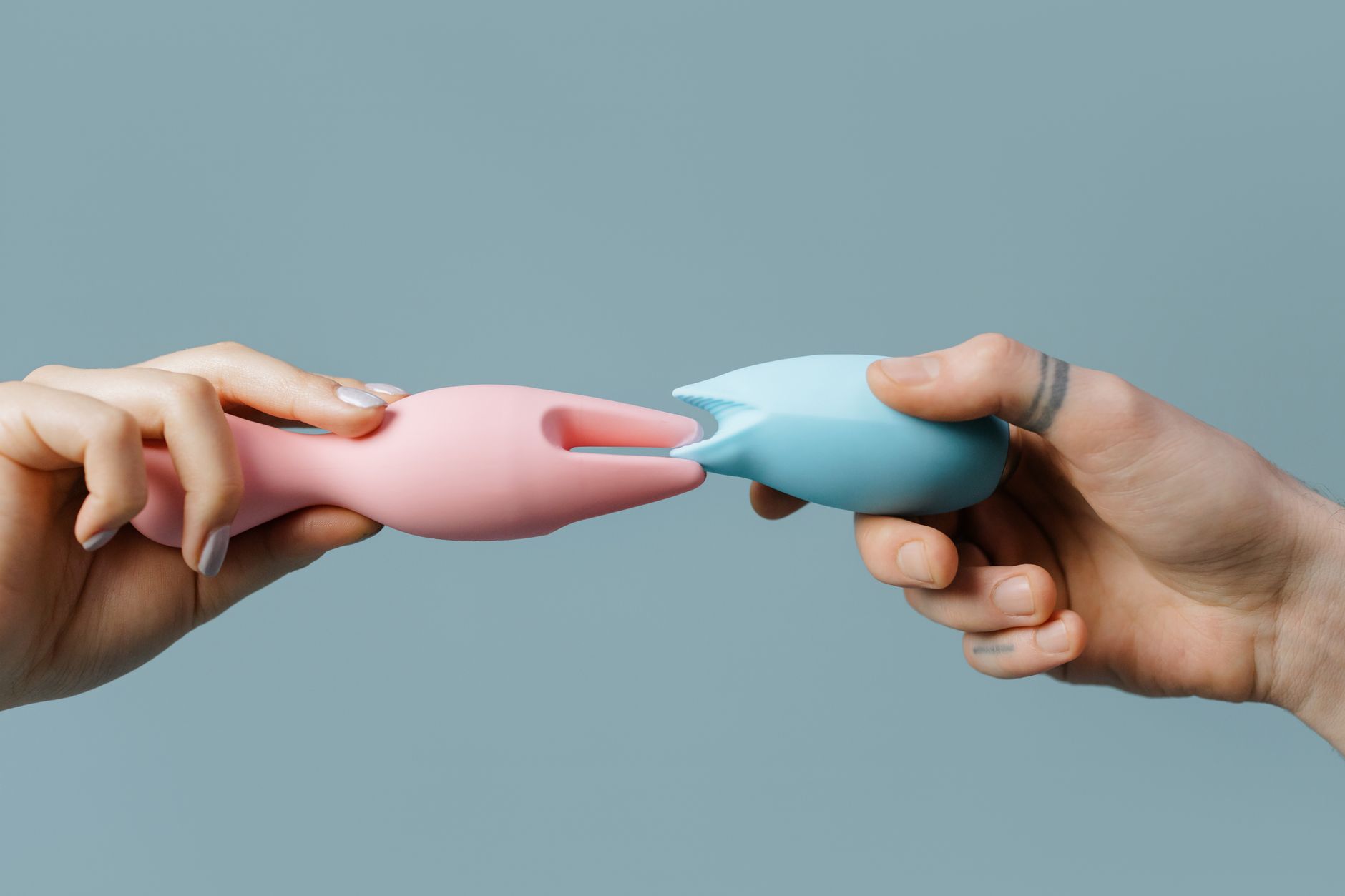Hand holding a fresh lemon on a soft pink background, symbolizing natural lubrication and sensuality