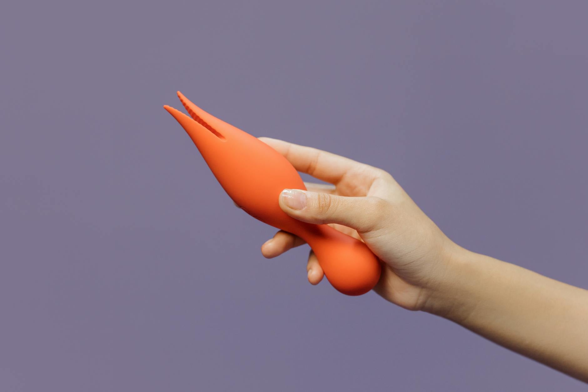 Hands holding a sleek blue clitoral vibrator, representing gentle self-care and reconnection with pleasure after heartbreak.