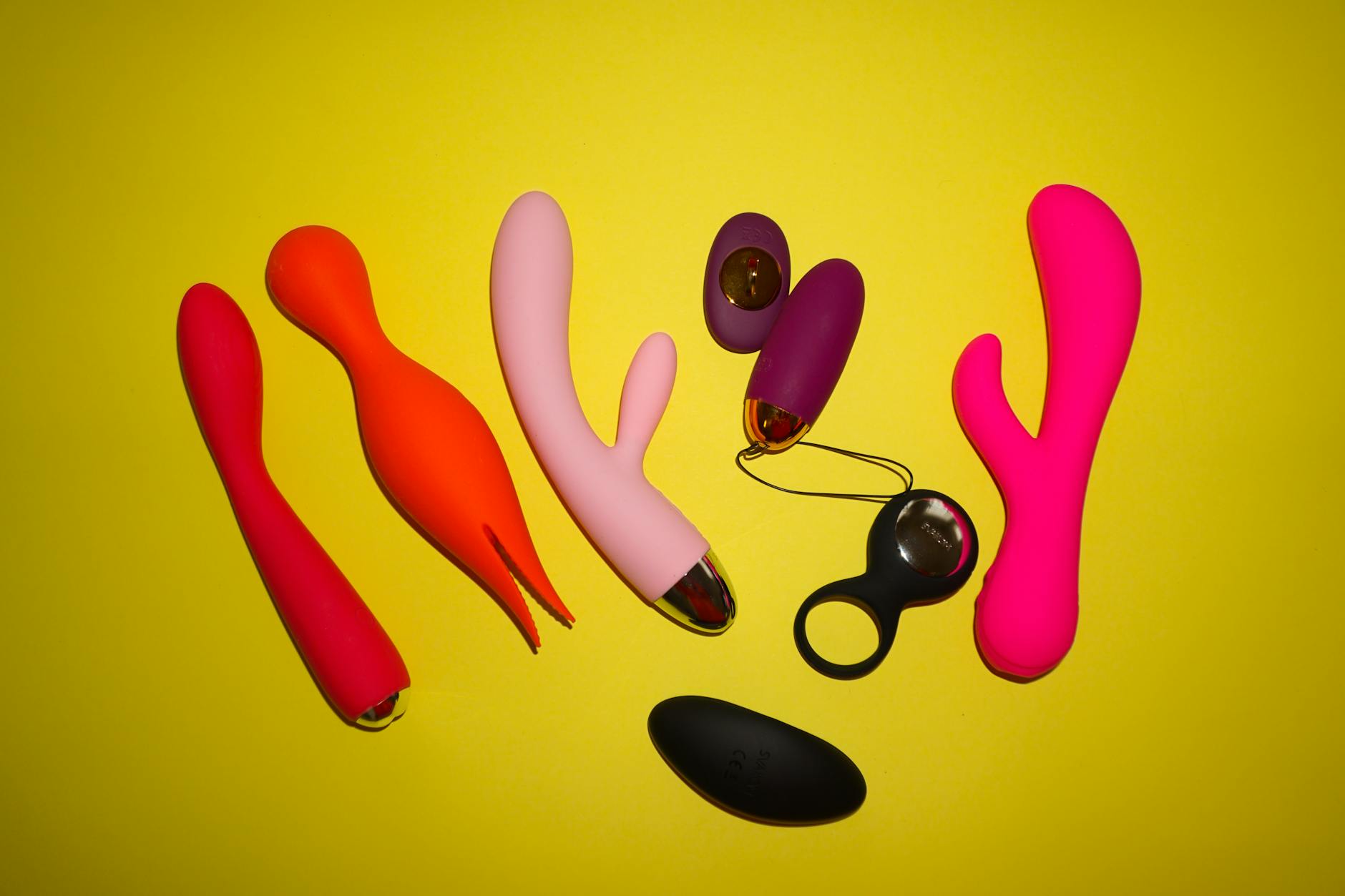 Studio display of colorful vibrators arranged artfully on a yellow background