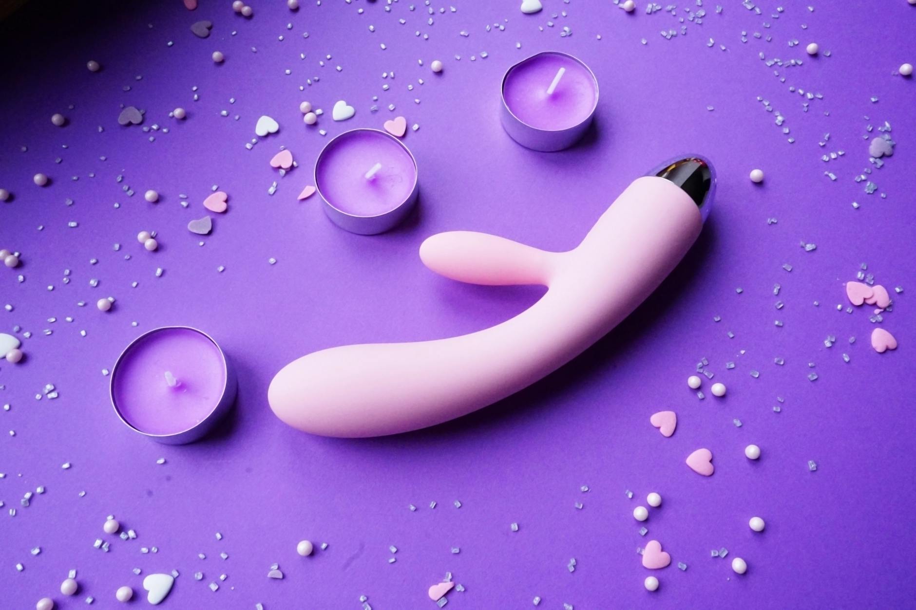 Pink lemon vibrator on purple background with heart confetti, showing suction-based design